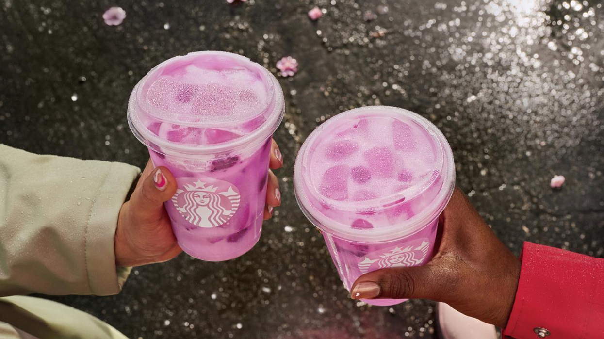 Two hands holding pink Starbucks drinks.