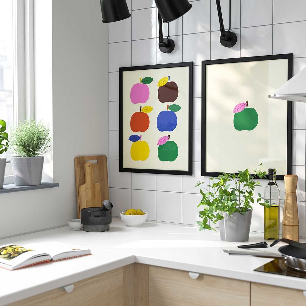 Two illustrations of apples hanging in a kitchen in IKEA FISKBO frames.