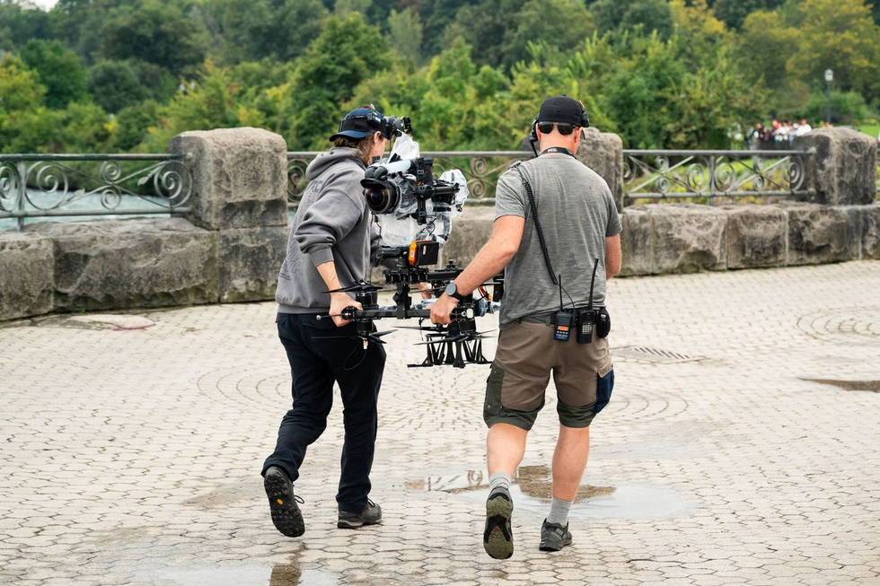 Two members of the Niagara Takes Flight crew carry a camera mounted on a drone.