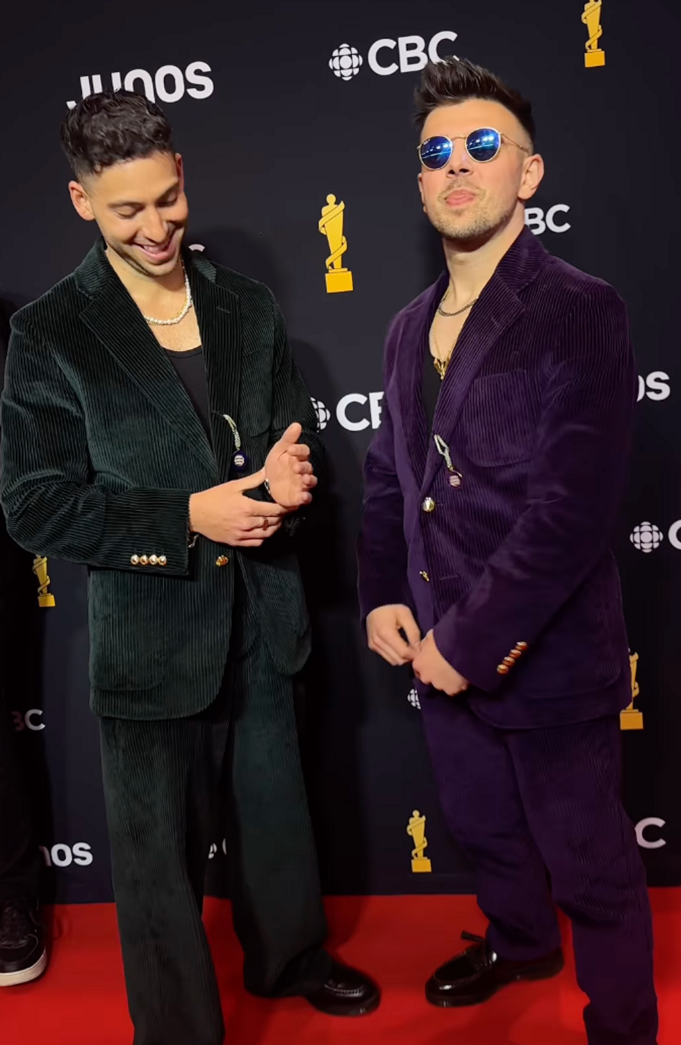 Two men posing for photos in their suits on the red carpet.