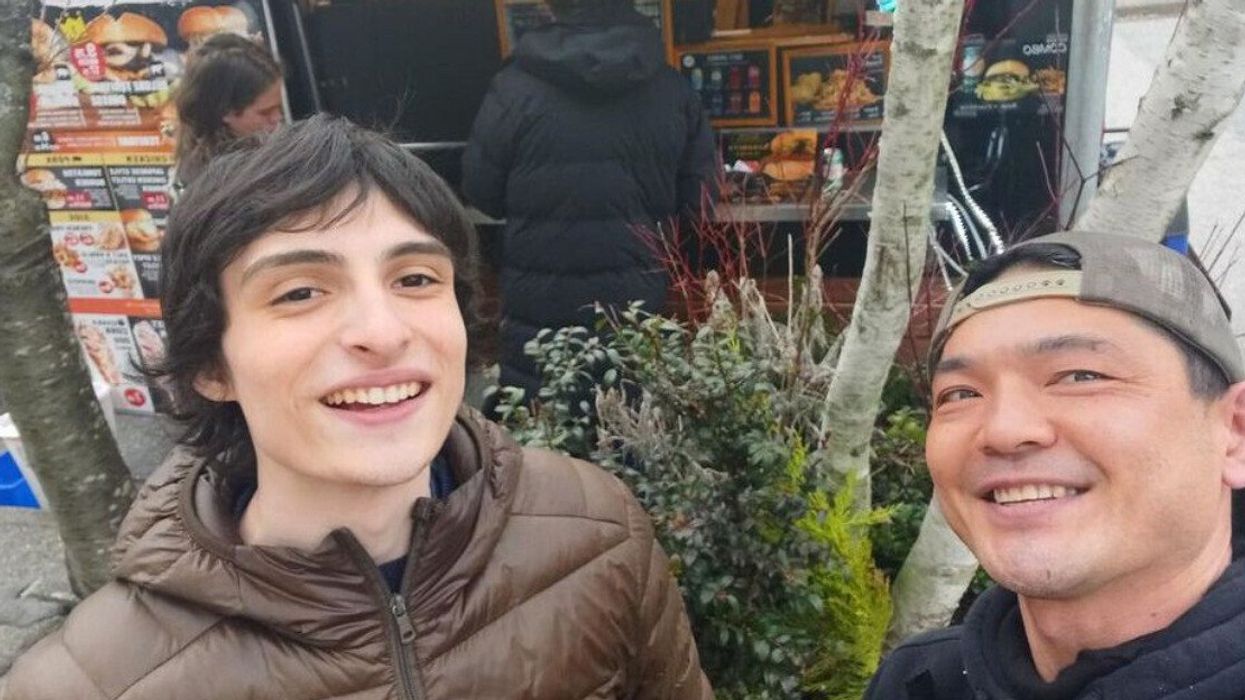 Two men smiling for the camera for a photo with a food truck behind them.