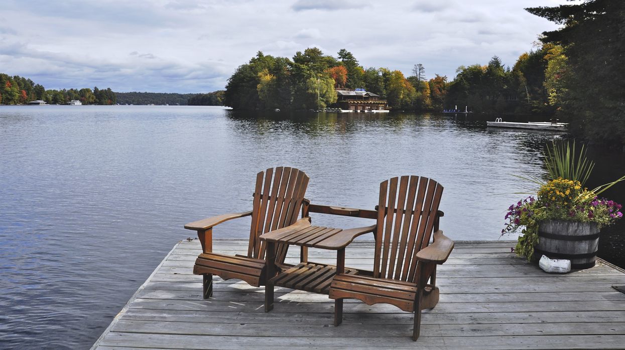 Two Muskoka chairs at the cottage by a lake.
