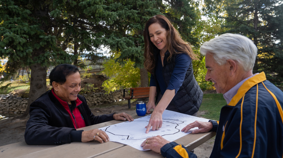 Two older men look at plans for a garden while a Rotary member points things out on the map.