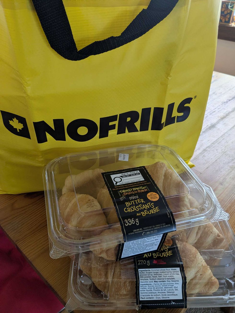 Two packages of croissants in front of a big yellow No Frills bag on a table