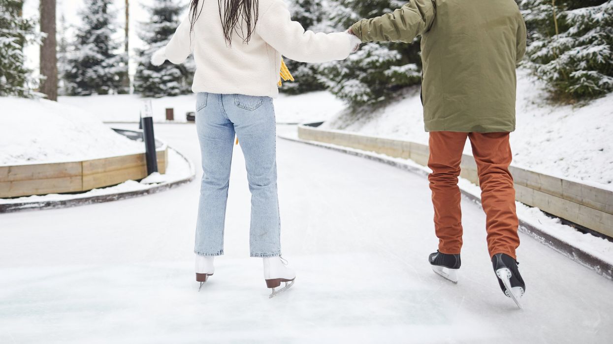 Two people holding hands while skating.