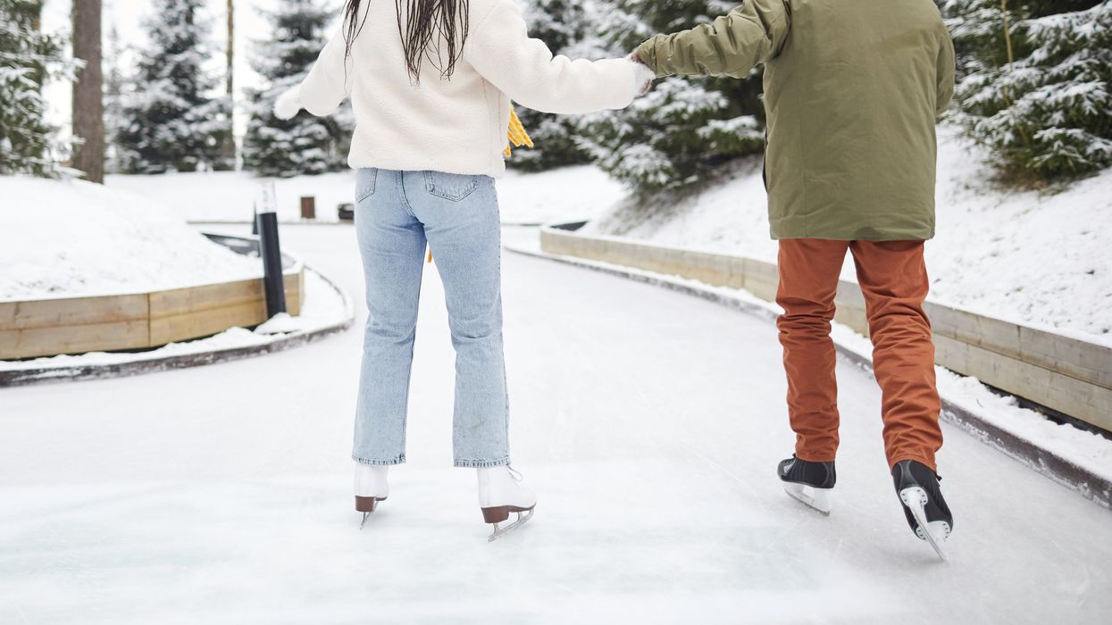 Two people holding hands while skating.