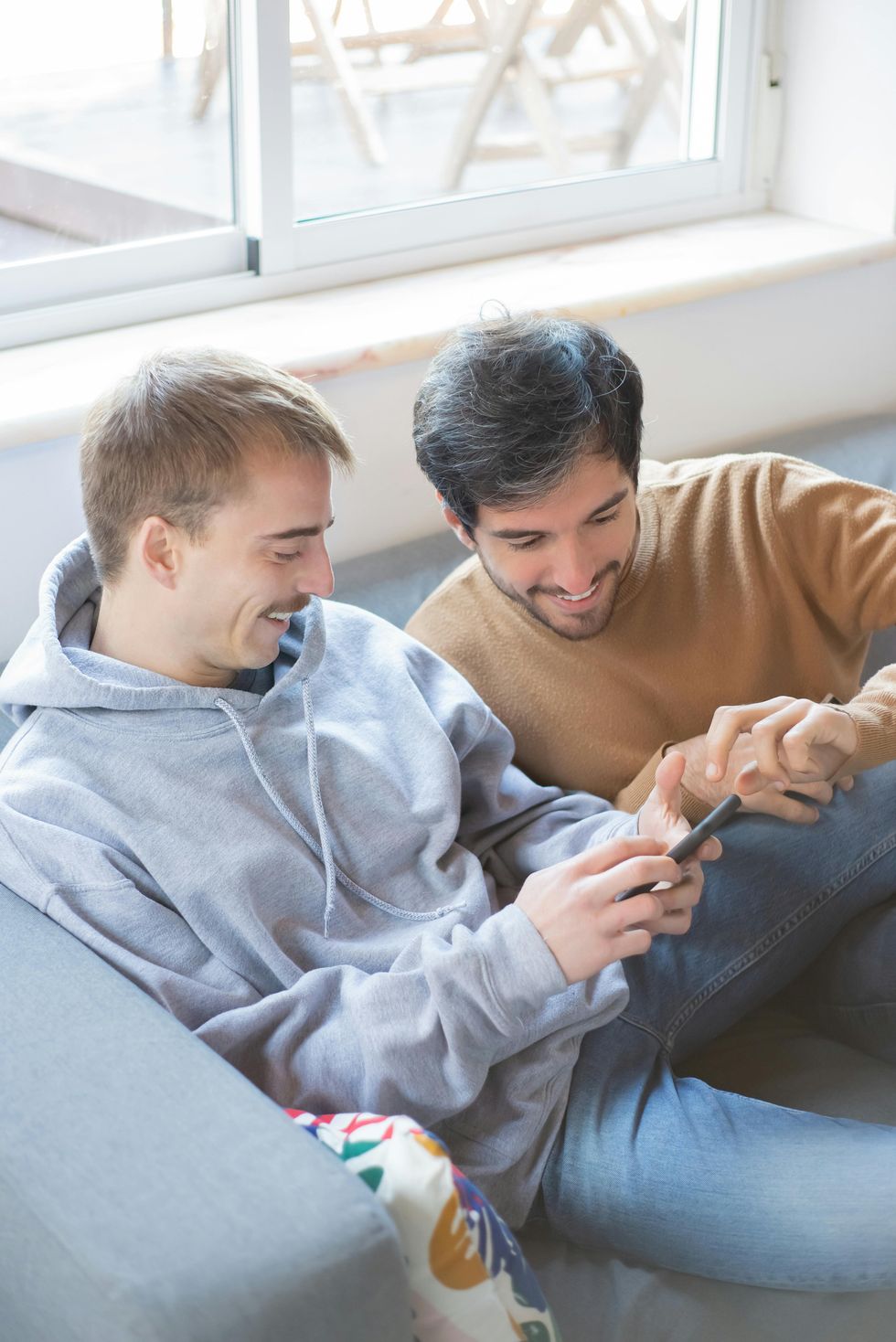 Two people on a couch looking at a mobile phone.