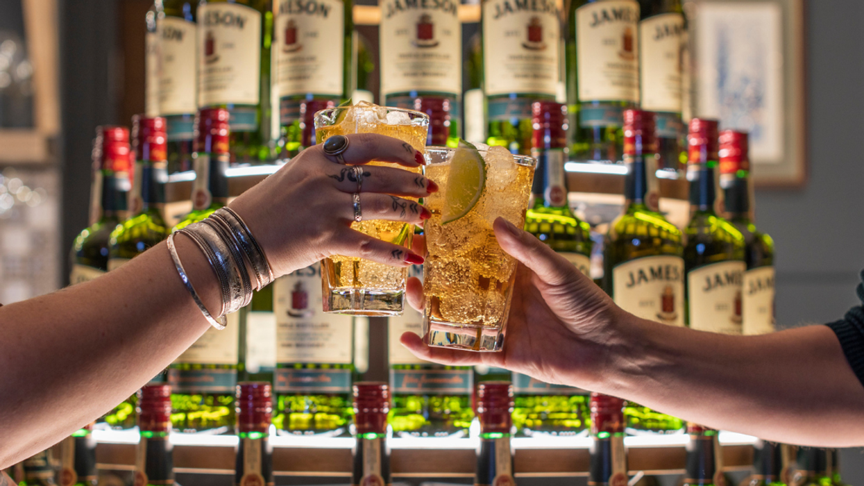 Two people raise their glasses in front of the Jameson tree.