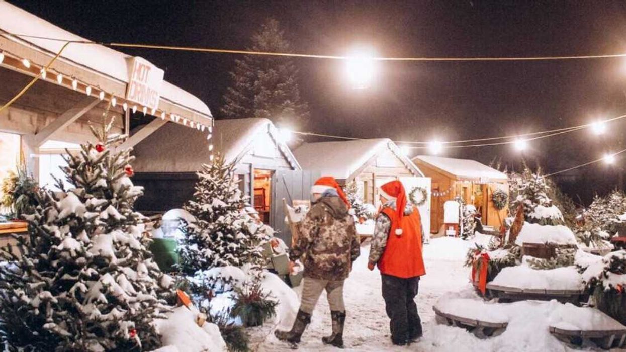 Two people standing in a snowy Christmas market.
