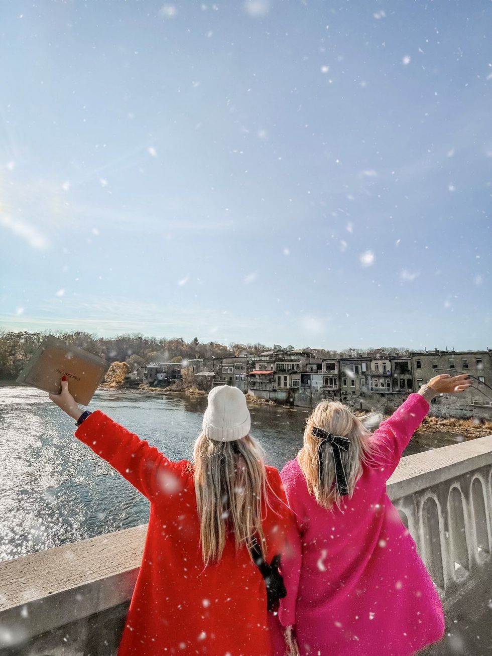 Two people standing on a bridge.