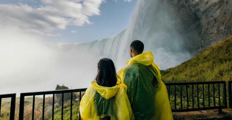 Two people standing on a platform by a waterfall.