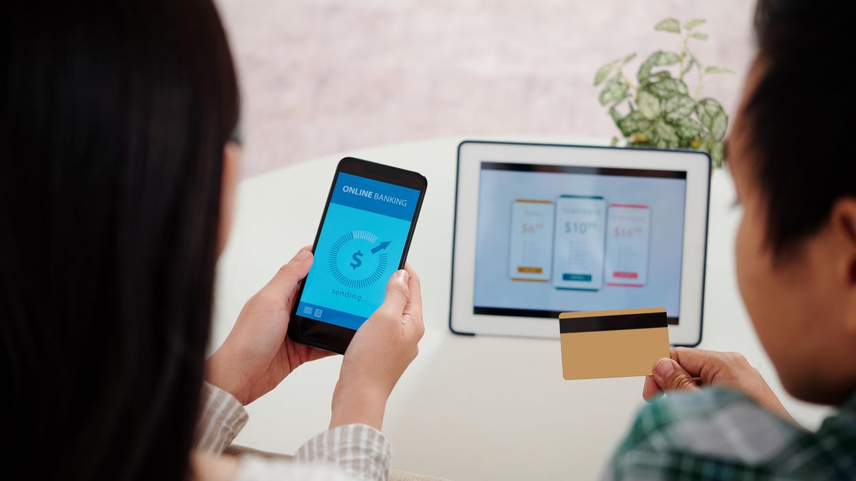 Two people with a smart phone and a credit card to subscribe to something on the tablet.