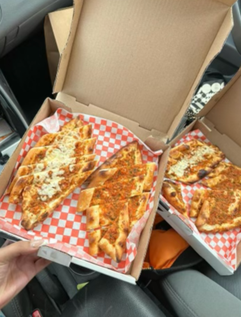 Two pizza boxes with sliced flatbreads inside.