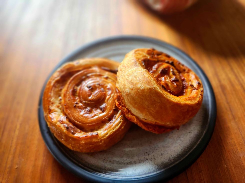 Two Savoury Pinwheel pinwheels on a plate on a wooden table.