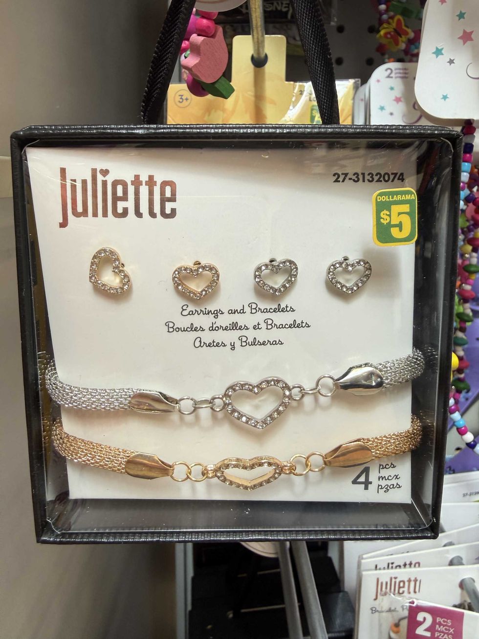 Two sets of heart earrings and matching bracelets in a box hanging on a store shelf.