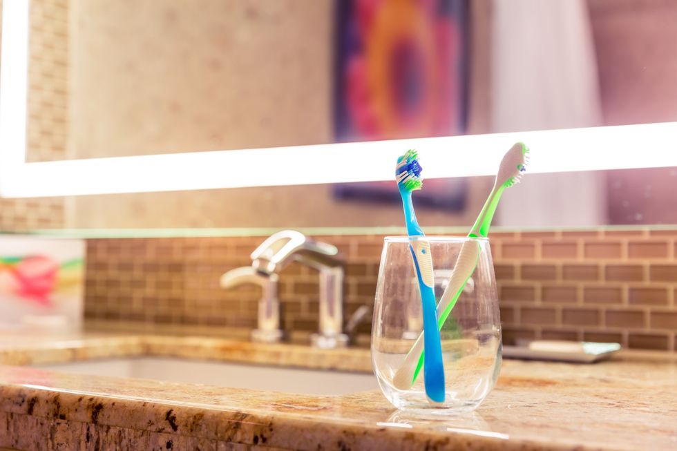 Two toothbrushes on a counter.