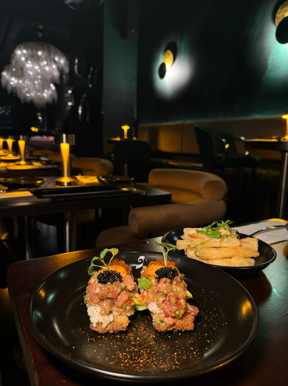 Two tostadas topped with rice, tuna and caviar, and a plate of thick-cut yuca fries behind.