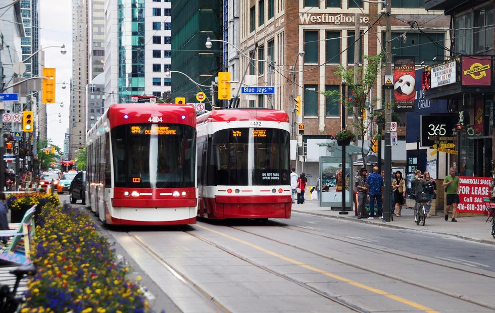 Two TTC streetcars passing go by one another on Blue Jays Way.