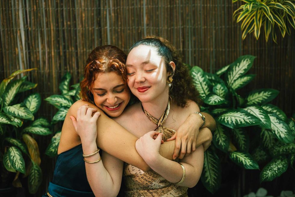 Two women happily hugging outdoors.