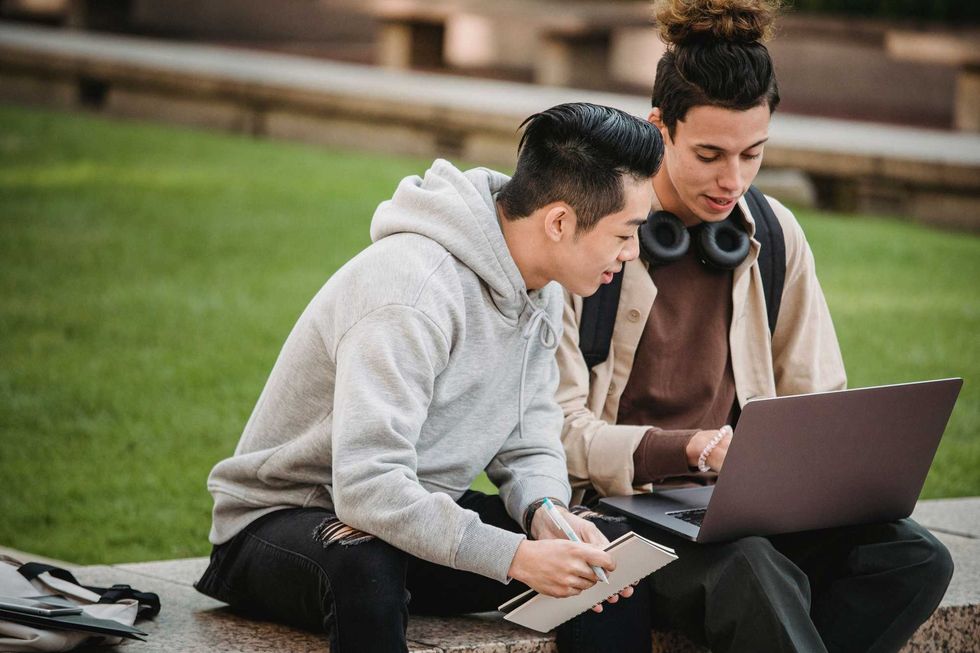 Two young men look at a laptop.
