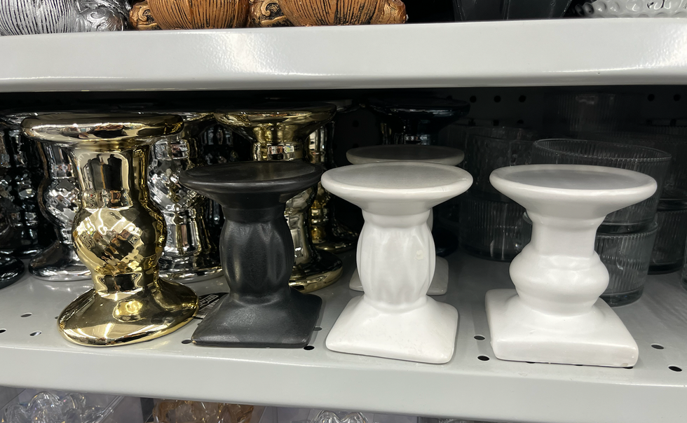 \u00c9tag\u00e8re du Dollarama o\u00f9 l'on voit trois mod\u00e8les de bougeoirs : dor\u00e9, noir et blanc.