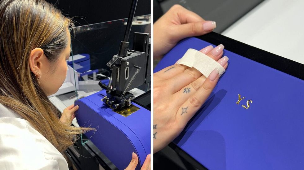 \u200bA Dyson team member uses a machine to emboss initials into an oval-shaped hair tool carry case. Right: A close up of A Dyson team members hands as they use a piece of tape to clean the front of a newly personalized Dyson presentation case.