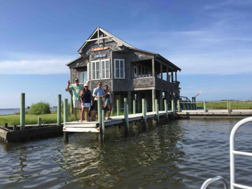\u200bA group stands on a dock outside of the private island's house.