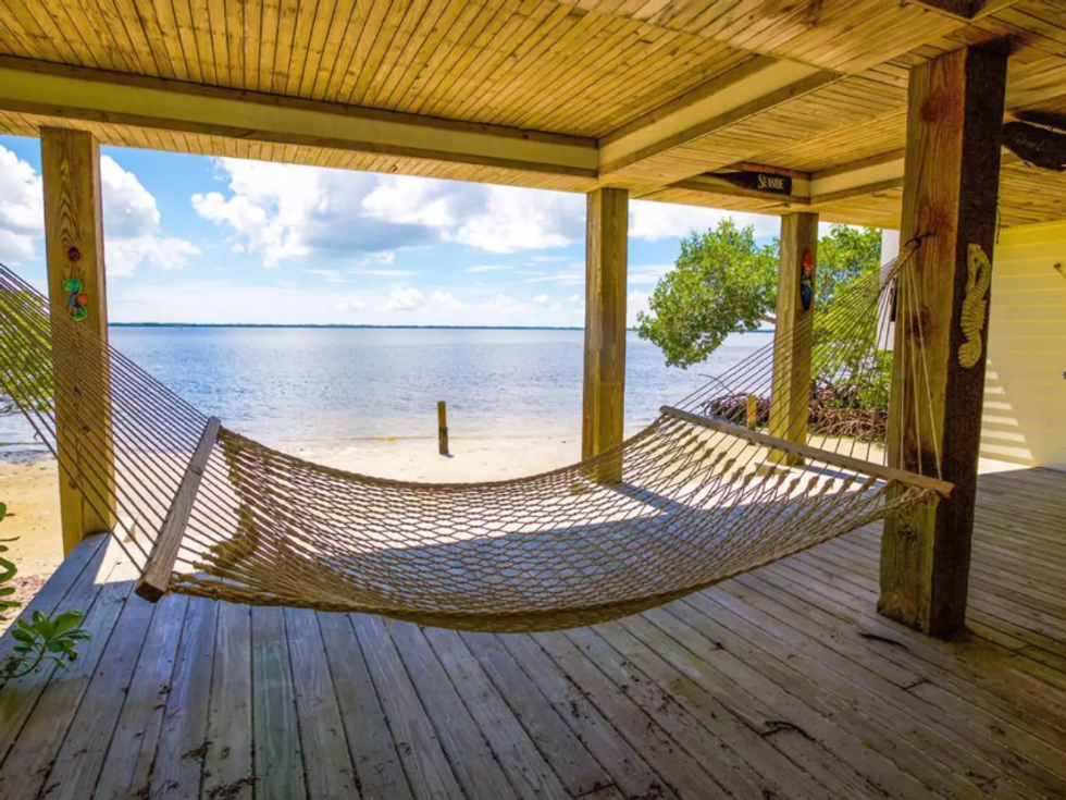 \u200bA hammock on the deck overlooking the shore and water.
