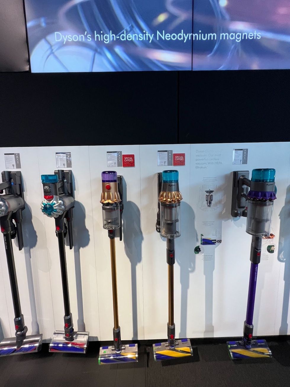 \u200bA wall display of Dyson cordless vacuums.