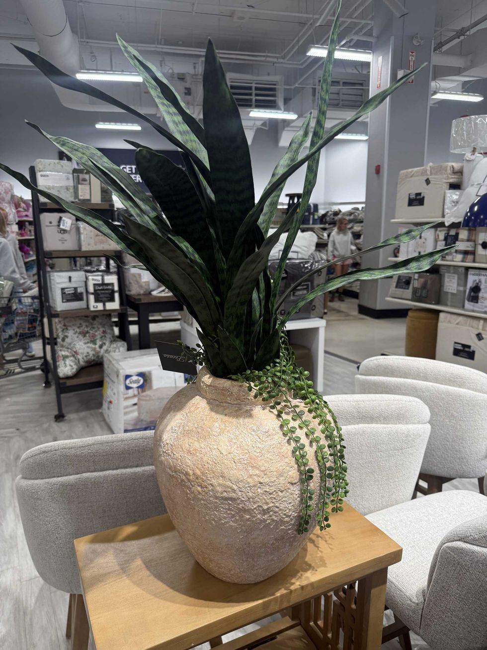 \u200bAn artificial plant in a large vase sitting on a table inside of a store.