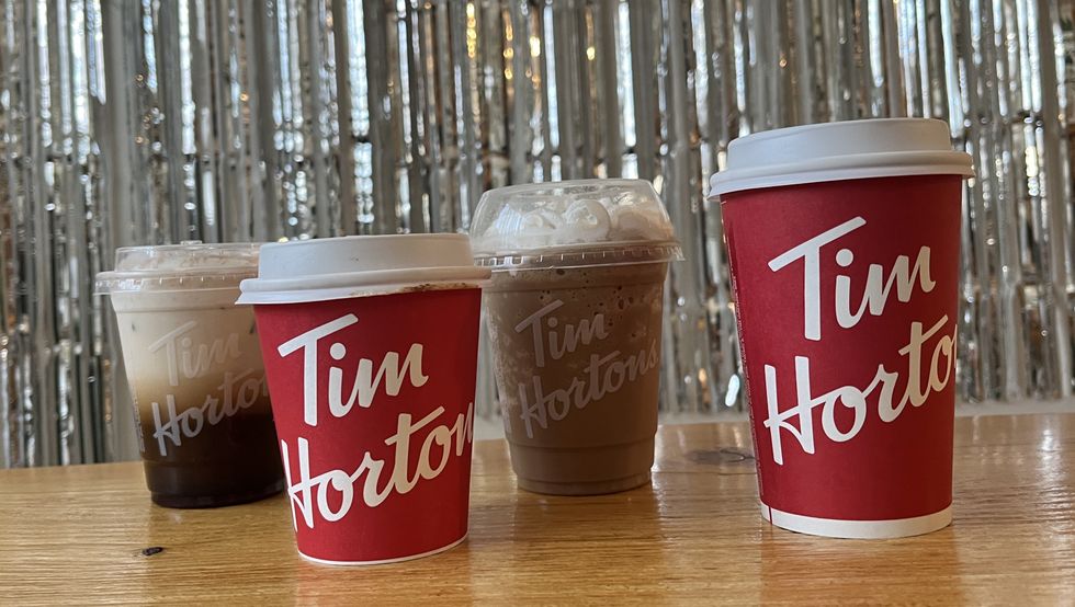 \u200bCaf\u00e9 infus\u00e9 \u00e0 froid au Baileys, latte au Baileys, cappuccino glac\u00e9 au Baileys et caf\u00e9 \u00e0 la cr\u00e8me au Baileys du Tim Hortons sur une table en bois devant un mur argent\u00e9.