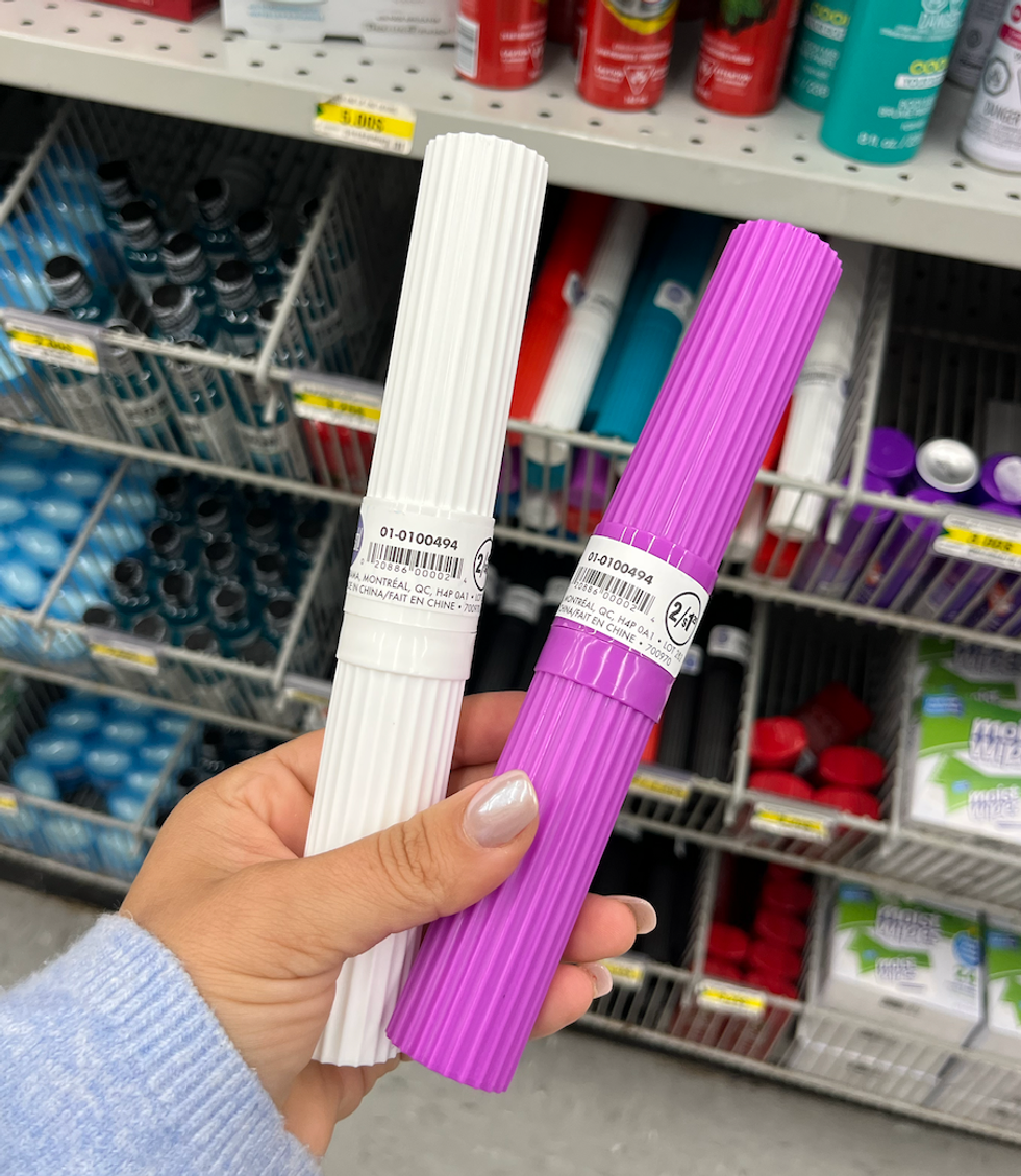 \u200bDeux bo\u00eetiers \u00e0 brosse \u00e0 dents, un mauve et un blanc, en plastique dans une main.