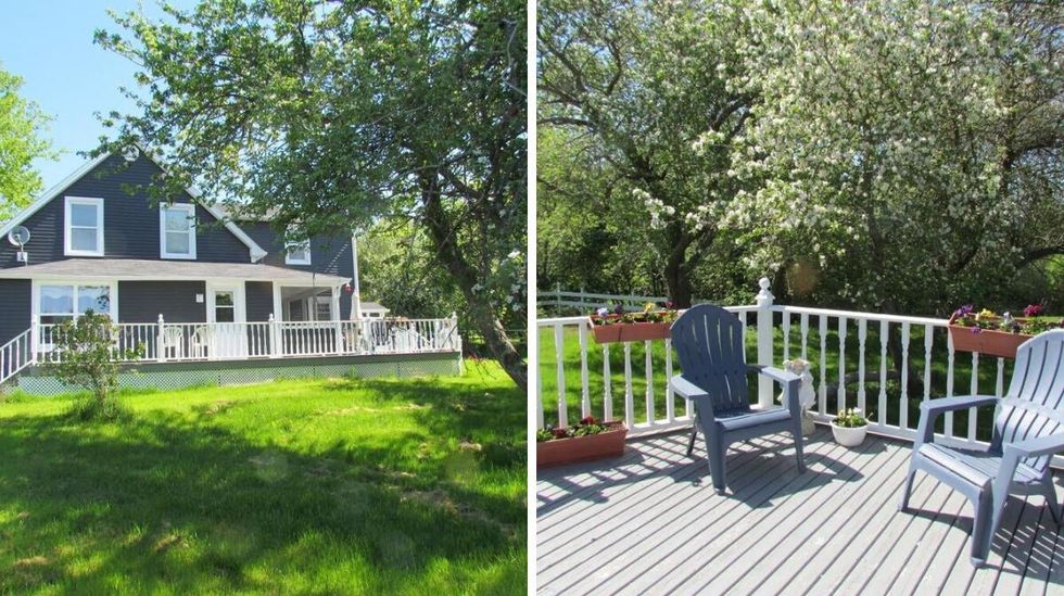 \u200bExterior of the house for sale. Right: Patio off the house with trees in the background.