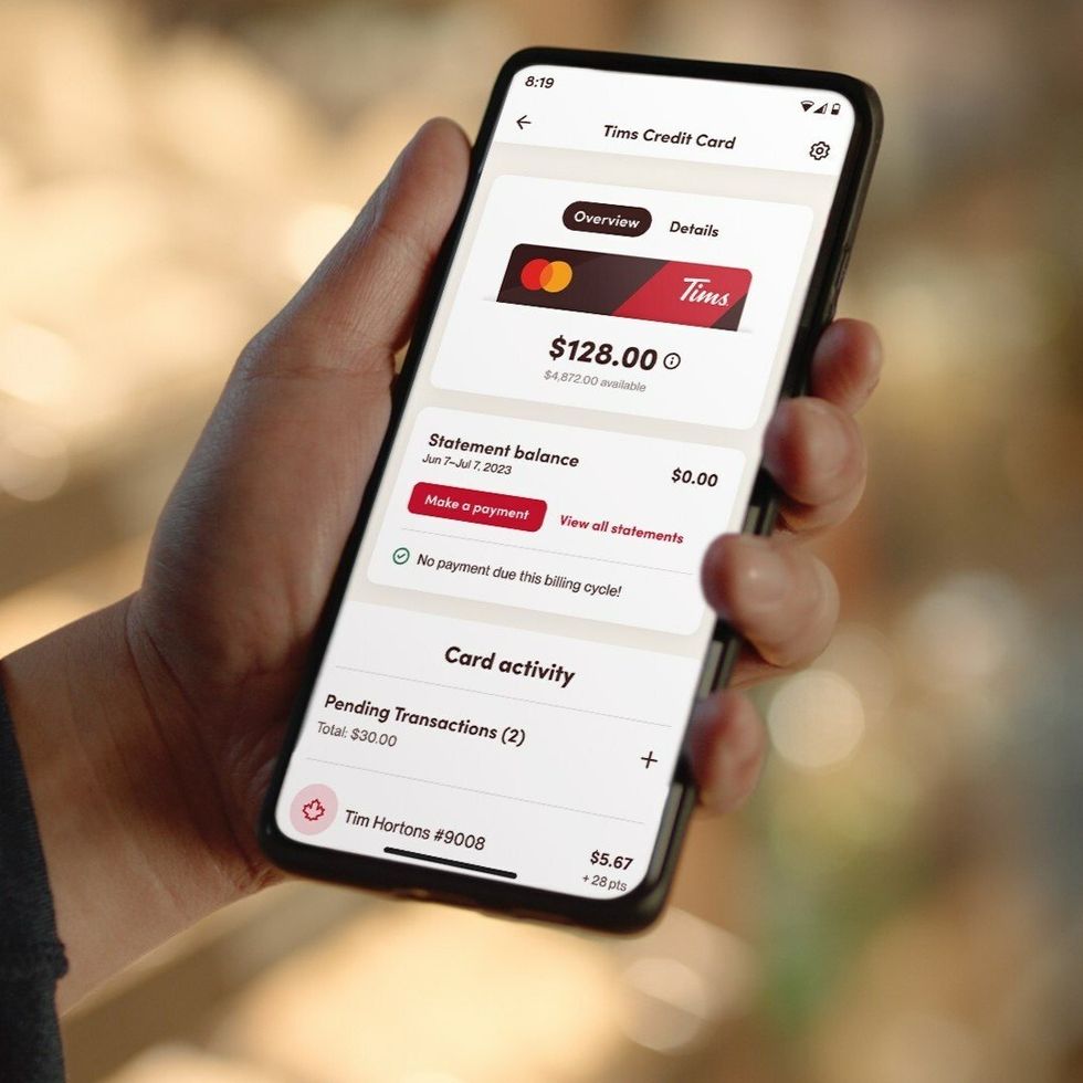 \u200bPerson holding a smartphone that has the Tim Hortons app.
