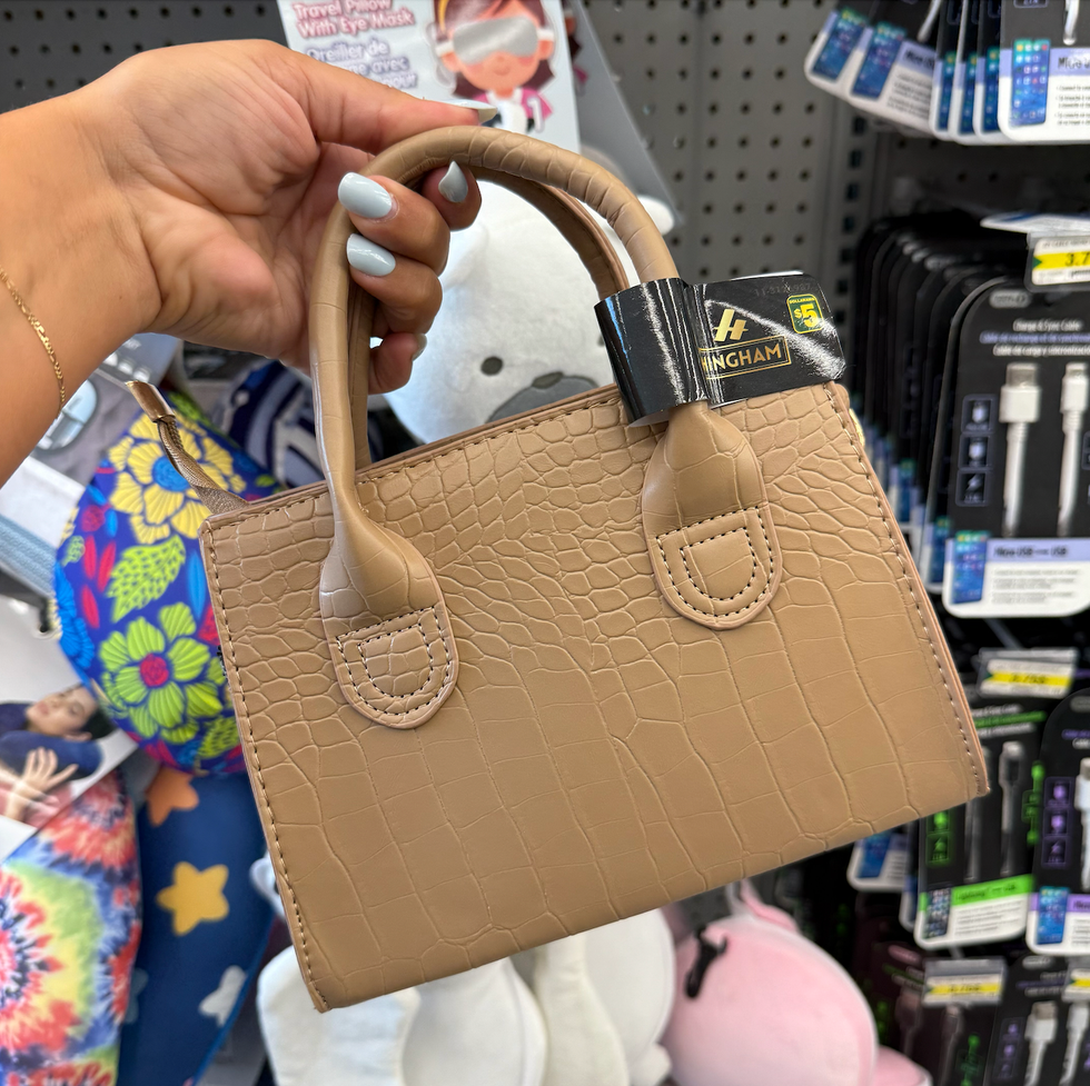 \u200bPetite sacoche beige en faux cuir dans une main au Dollarama.
