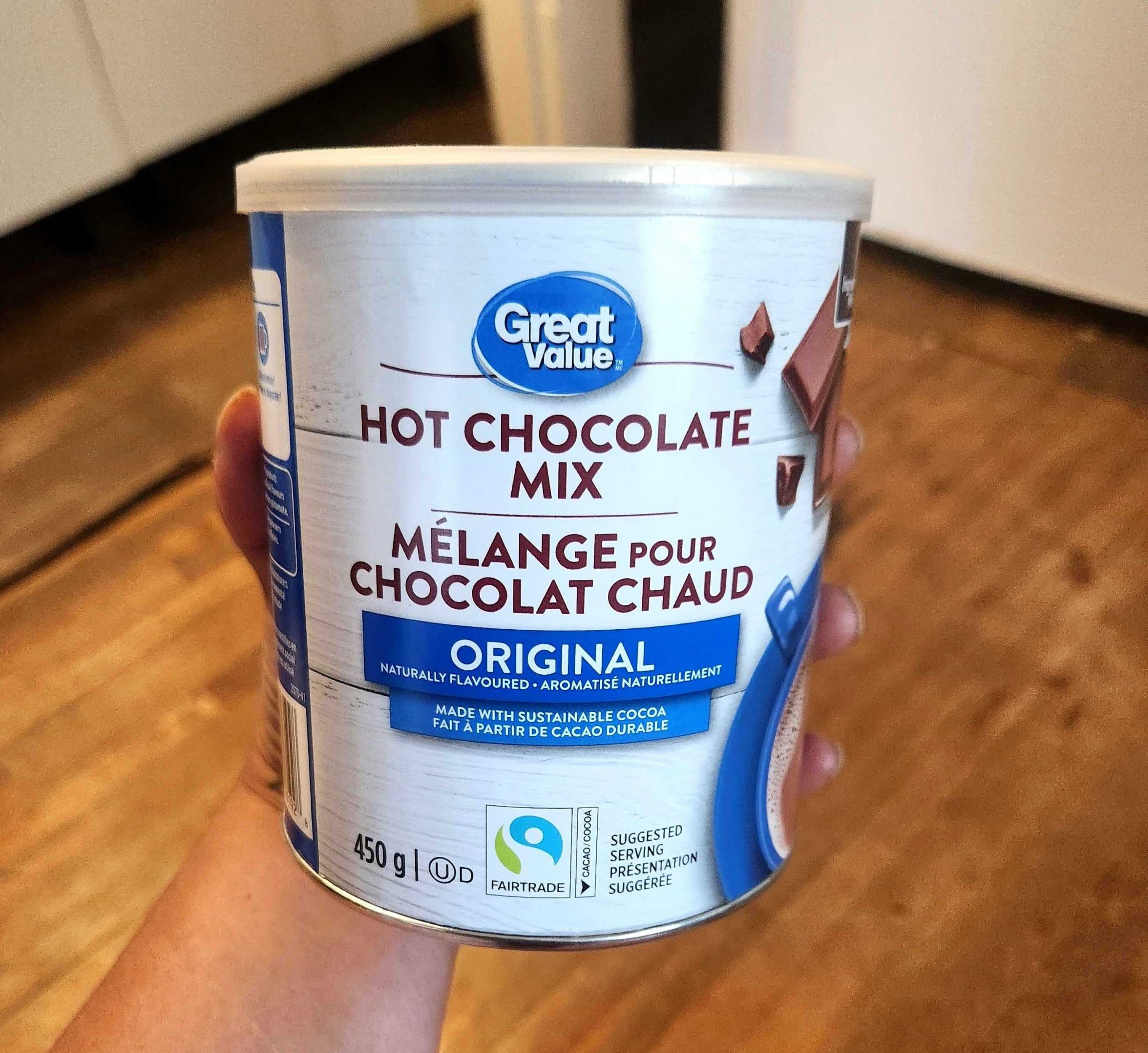 \u200bSarah holding a tin of Great Value brand hot chocolate mix from Walmart, 450 grams for $4.27.