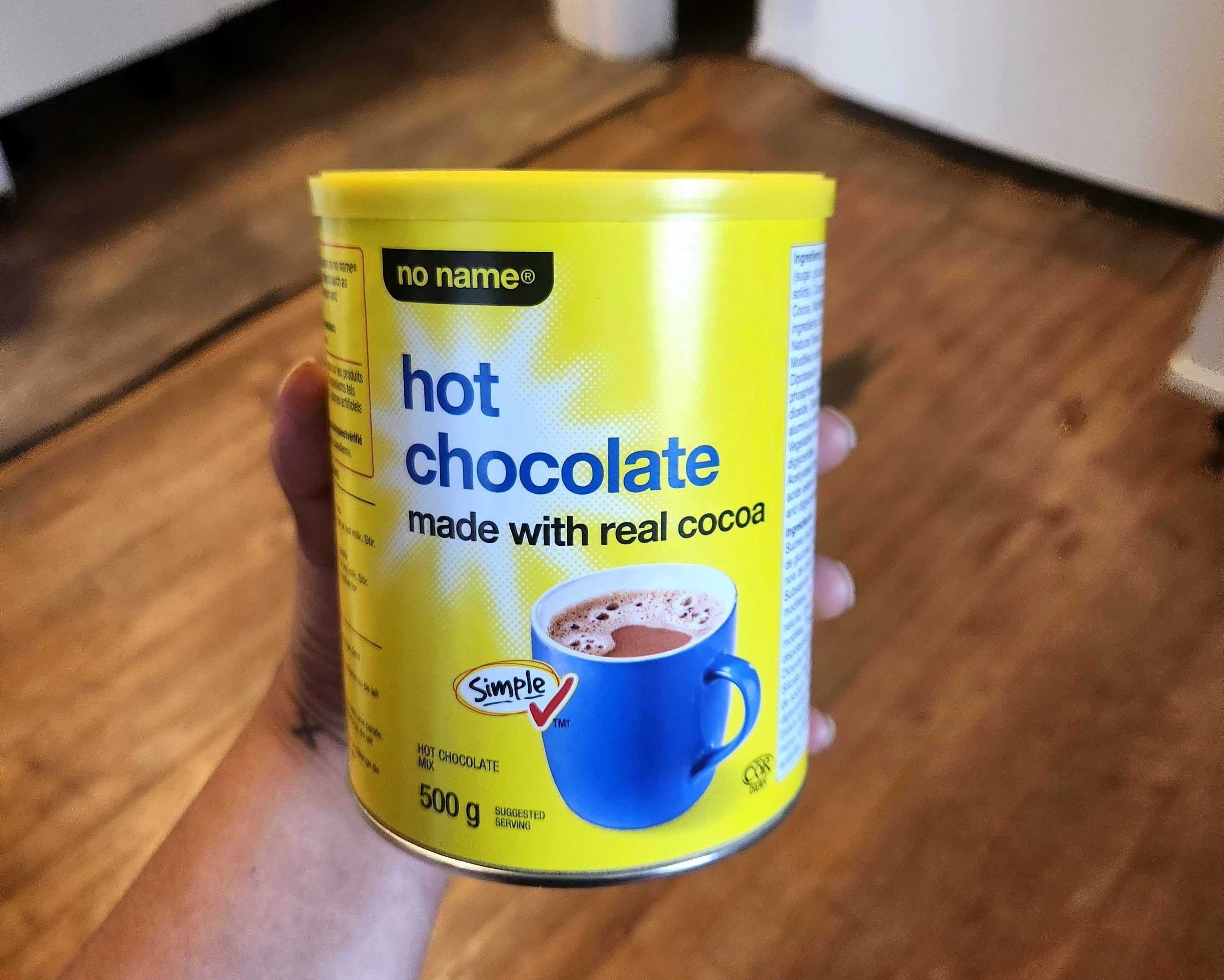 \u200bSarah holding a tin of no name hot chocolate mix from Loblaws, $3.99 for 500 grams.