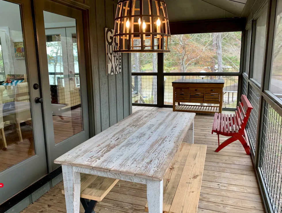 \u200bThe porch overlooking the lake with a rustic dining table and chairs.