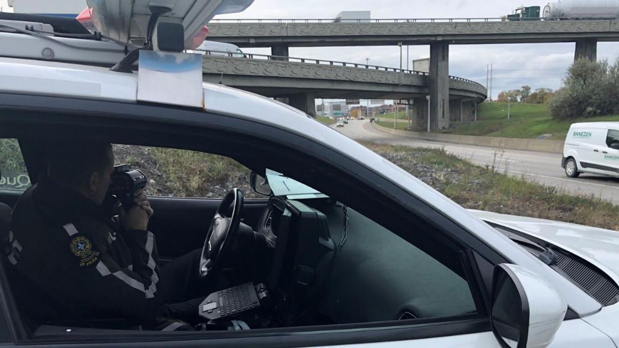 Un agent de police avec un radar dans une autopatrouille de la Sûreté du Québec.