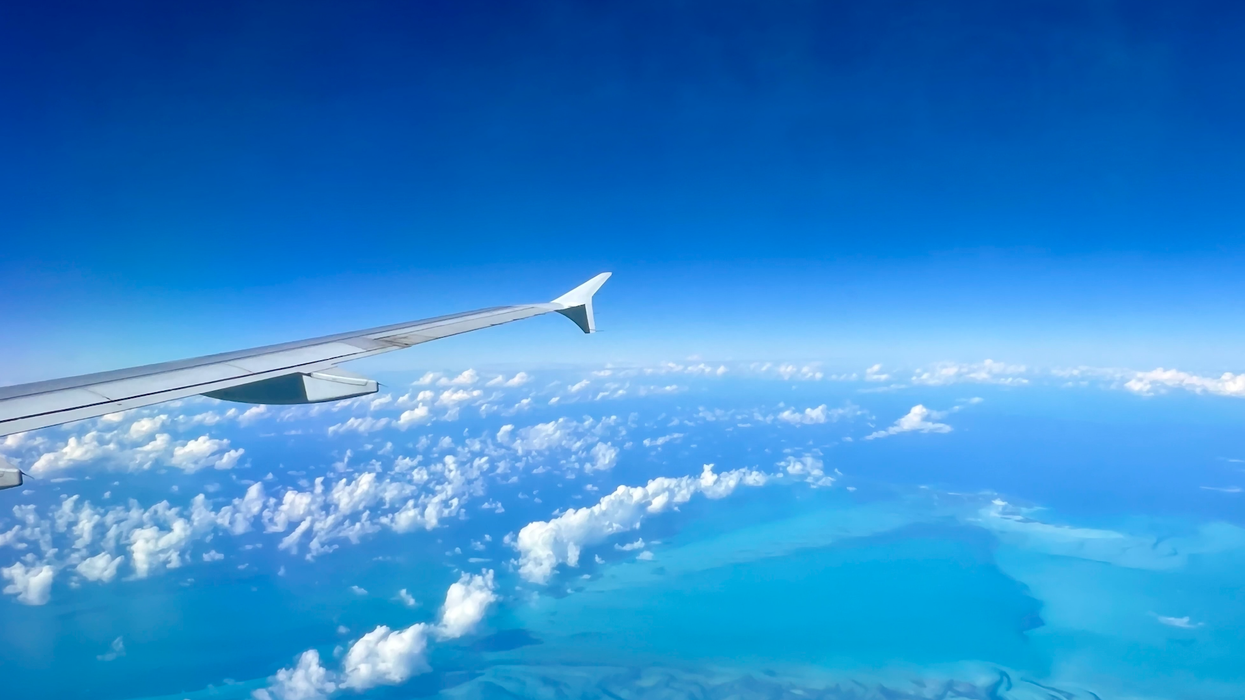 Un aileron d'avion surplombe les nuages et la mer.