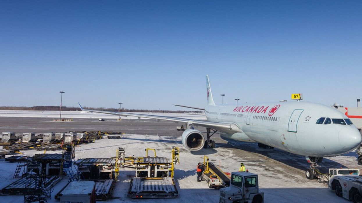 Un avion d'Air Canada avec de nombreux équipements de transport sur le tarmac de l'aéroport de Montréal.