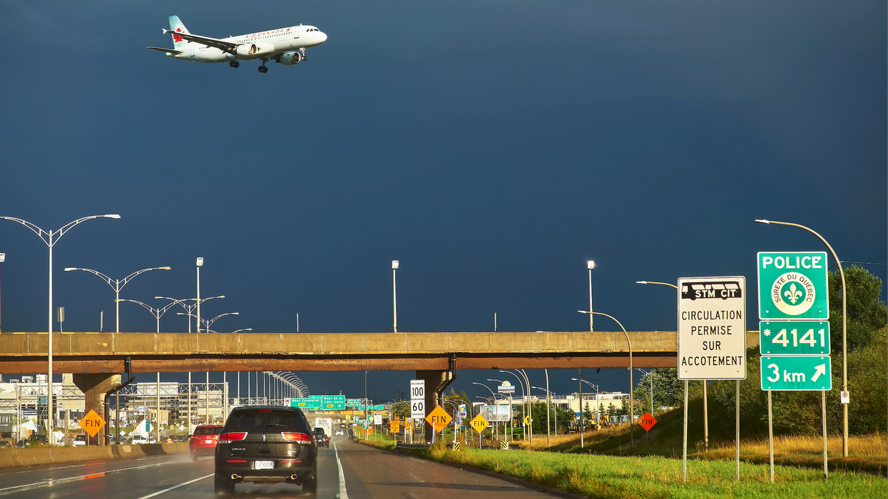 Un avion dans un ciel orageux surplombe une autoroute à Montréal.