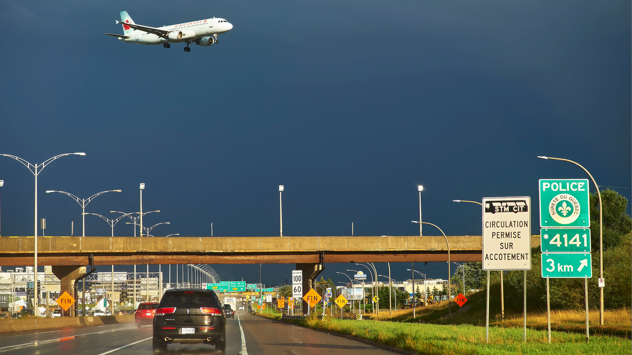 Un avion dans un ciel orageux surplombe une autoroute à Montréal.