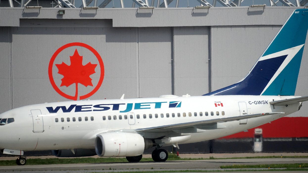 Un avion de WestJet sur une piste d'aéroport devant un logo d'Air Canada.