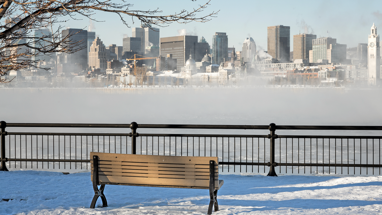Un banc de parc devant un paysage hivernal au centre-ville de Montréal.