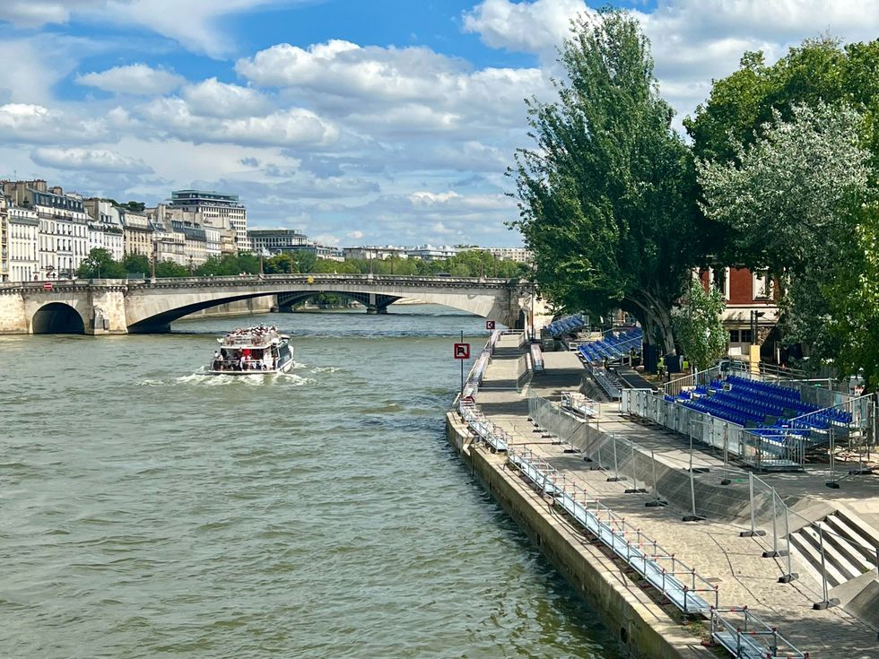 Un bateau vogue sur la Seine et des gradins sont install\u00e9s aux abords du fleuve.
