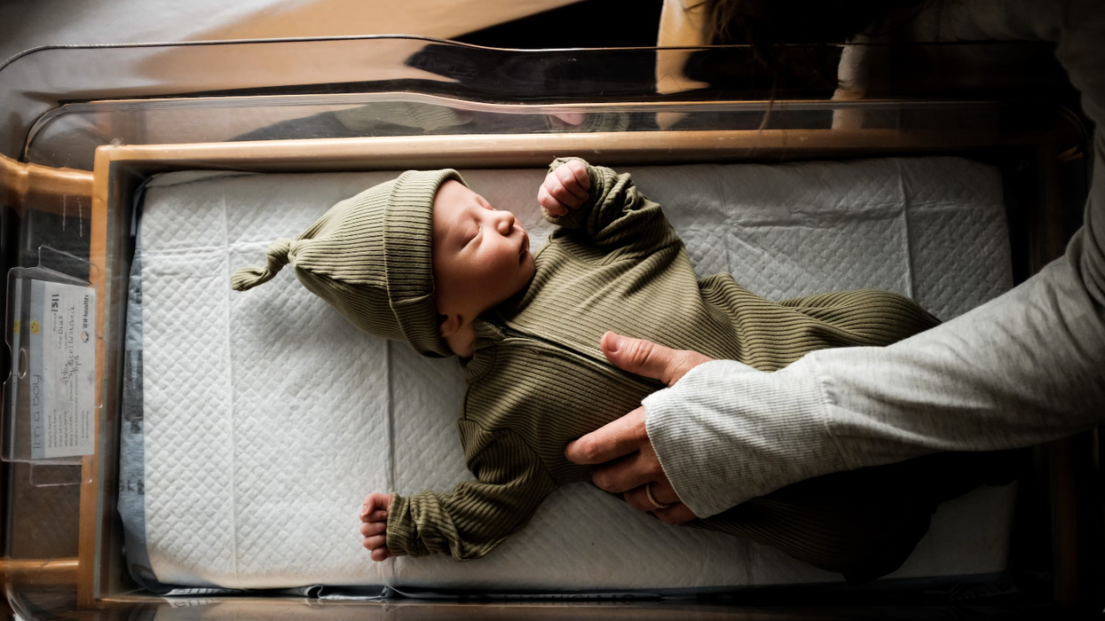 Un bébé avec un bonet vert sans un lit à l'hôpital.