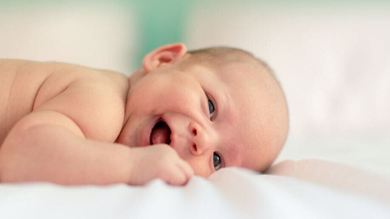 Un bébé couché sur le ventre et souriant.