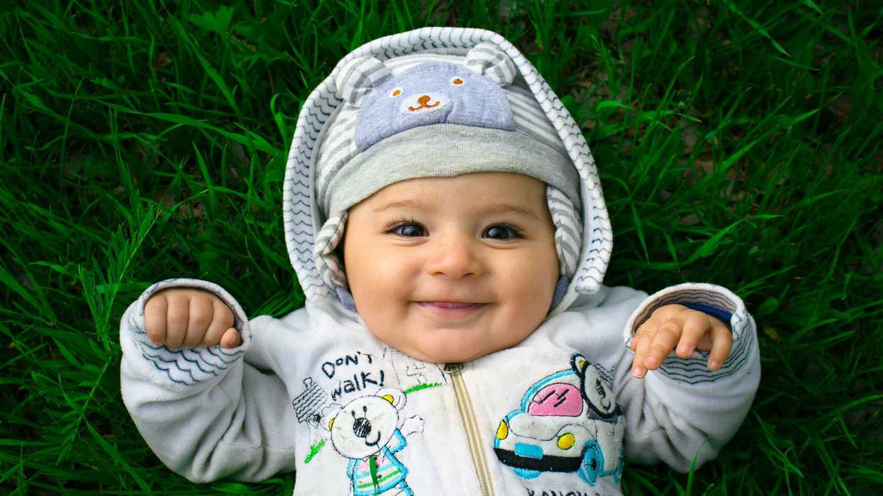 Un bébé souriant couché dans l'herbe.