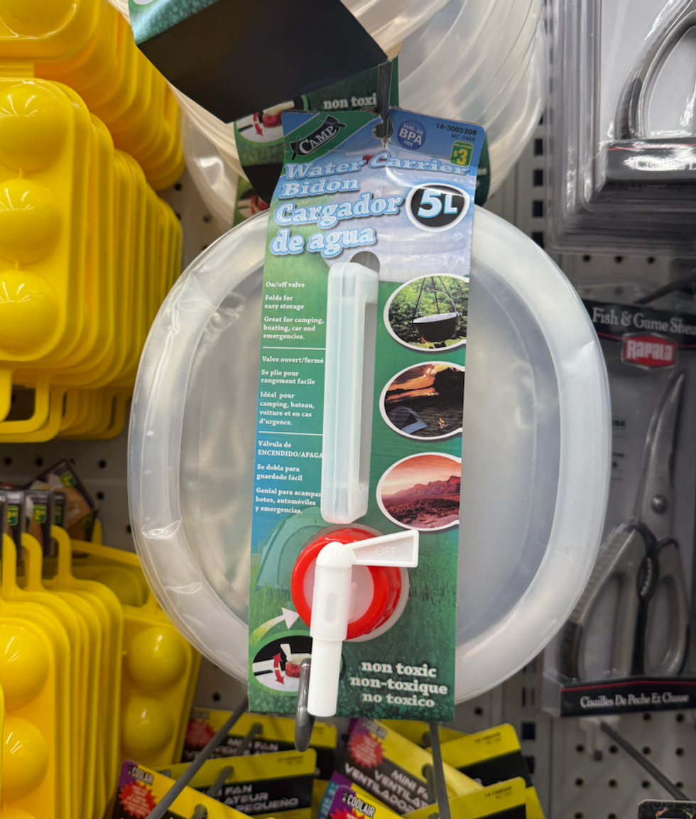 Un bidon d\u2019eau transparent avec robinet rouge et blanc, accroch\u00e9 en rayon.
